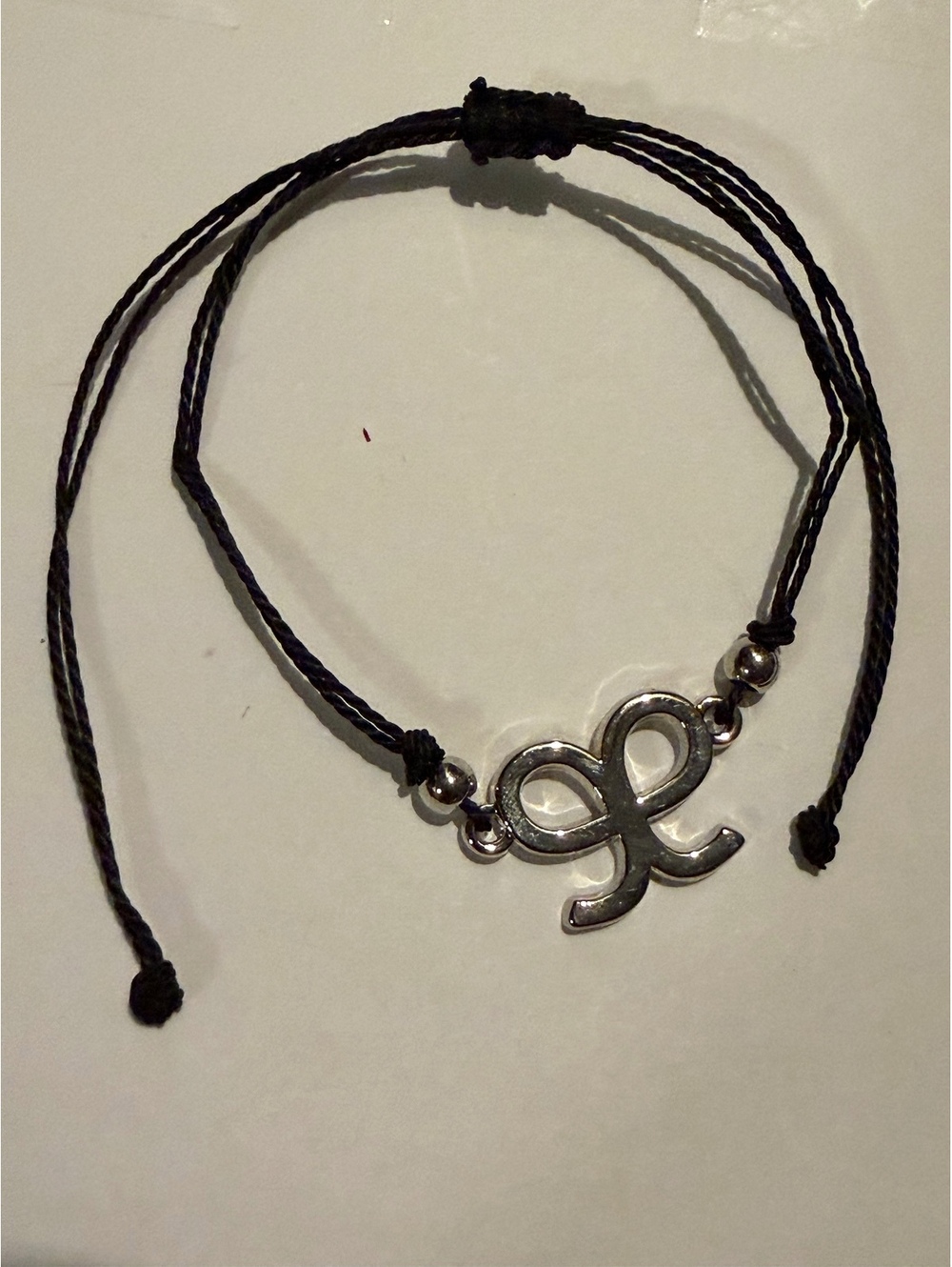 Black cord bracelet with silver tone symbol charm
